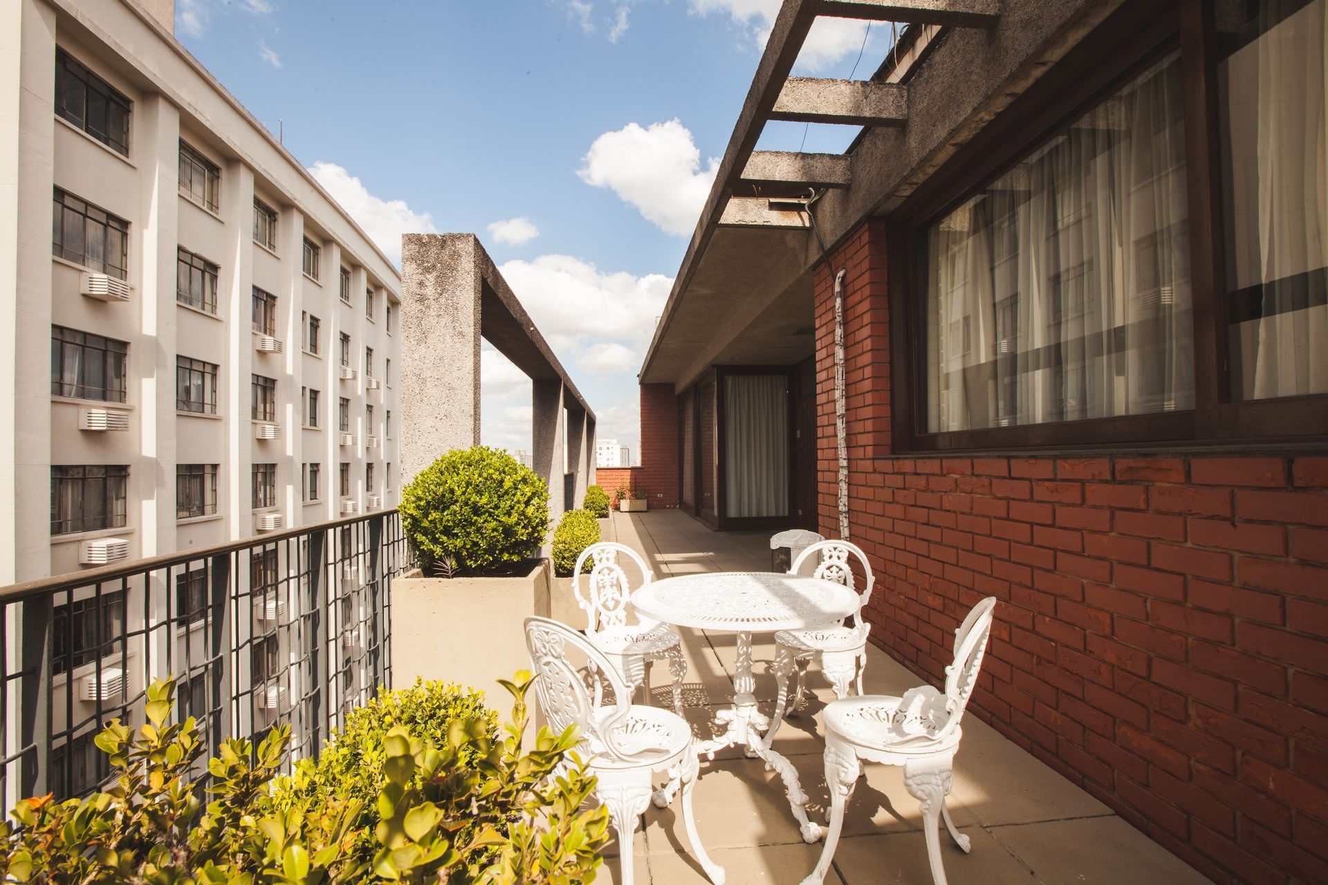 Uma varanda com mesa e cadeiras em frente a um prédio de tijolos.