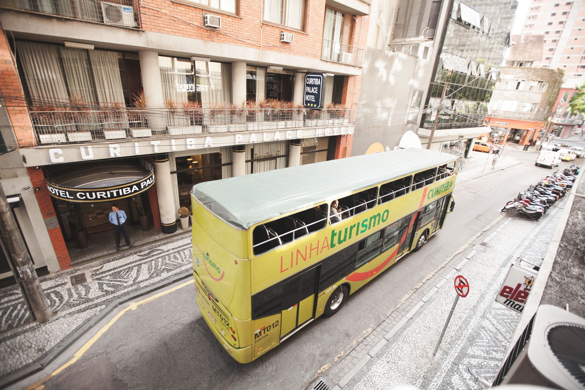 Um ônibus amarelo de dois andares está passando por uma rua da cidade