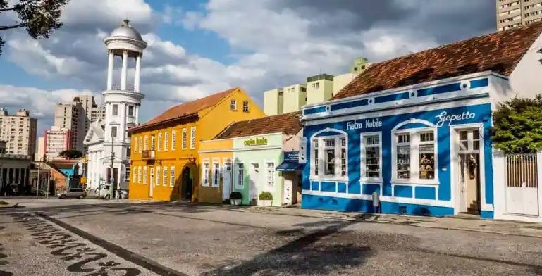 Uma fileira de edifícios coloridos está alinhada em uma rua da cidade.