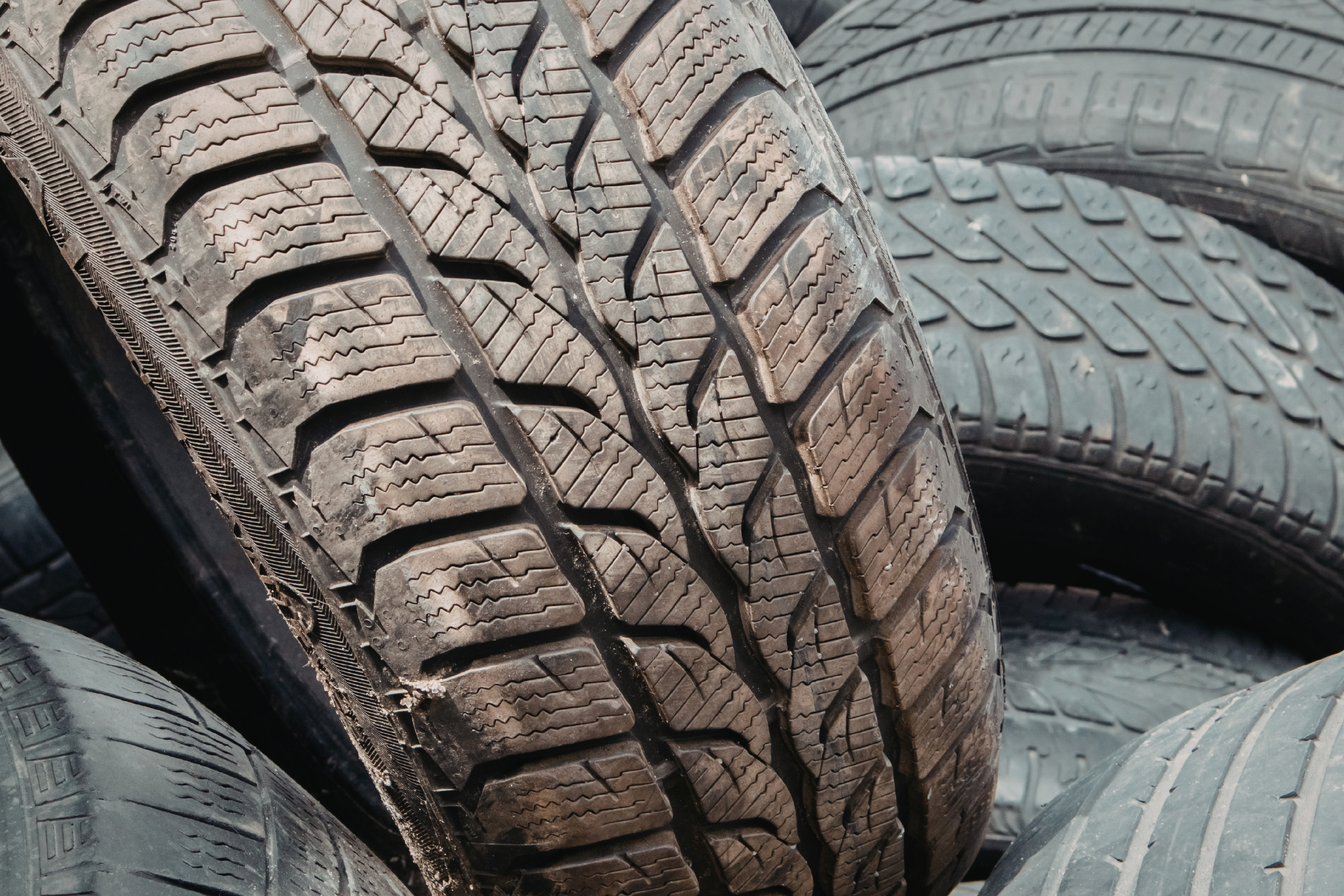 Pile of used tires with various tread patterns.