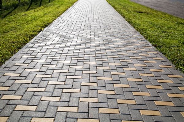 A brick walkway going through a grassy area