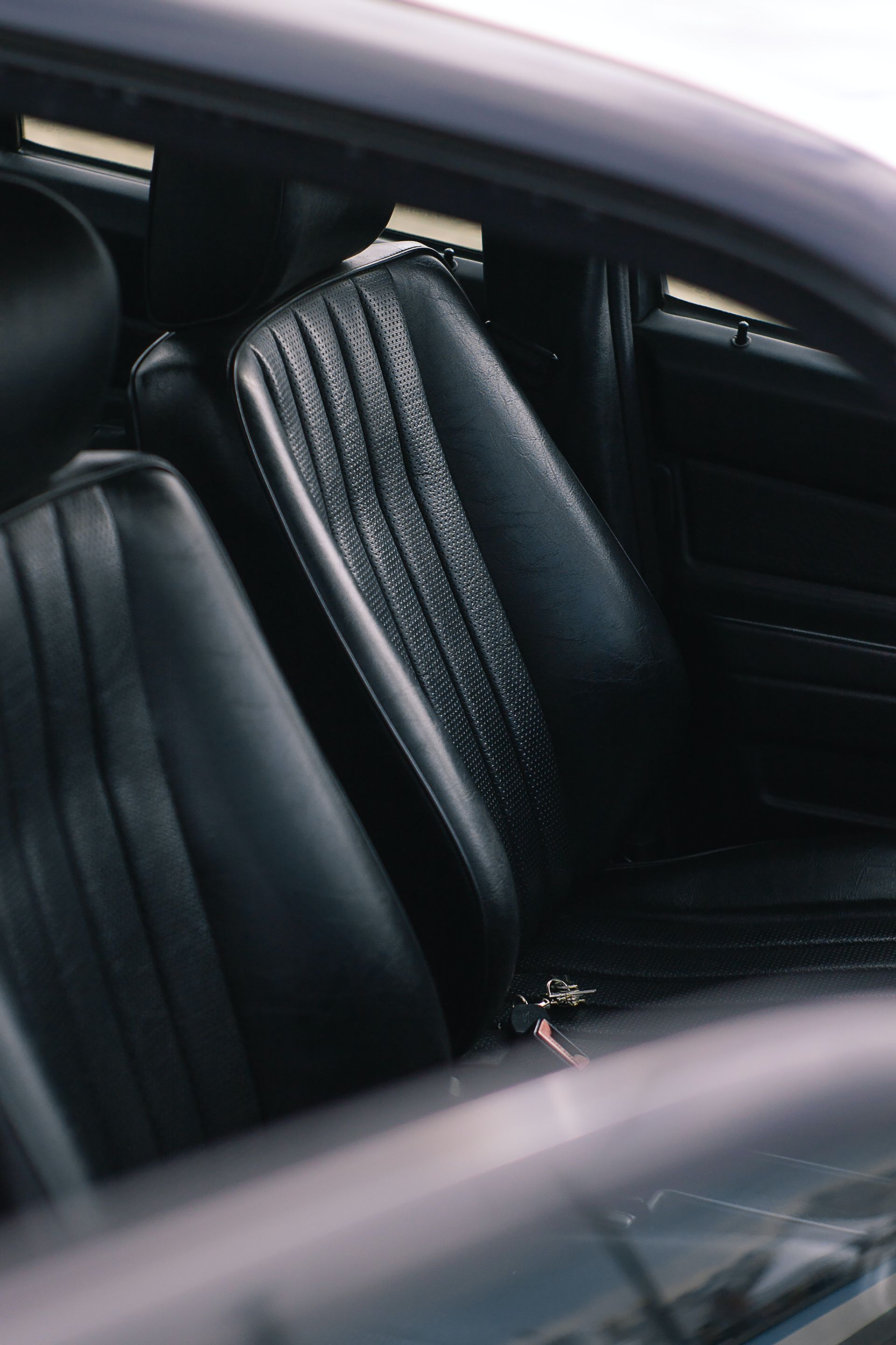 Black car seats, wet with condensation, inside a dark-colored vehicle.