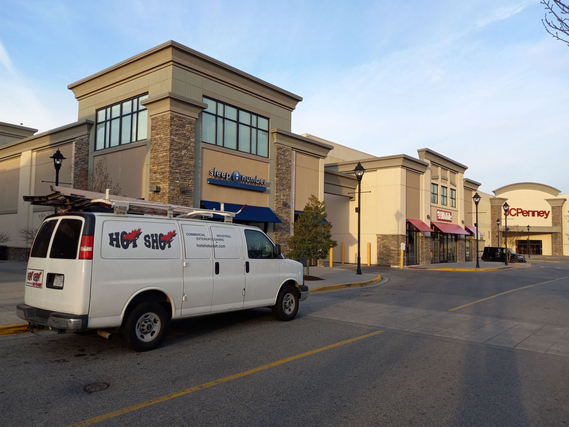 A white van is parked in front of a large building.