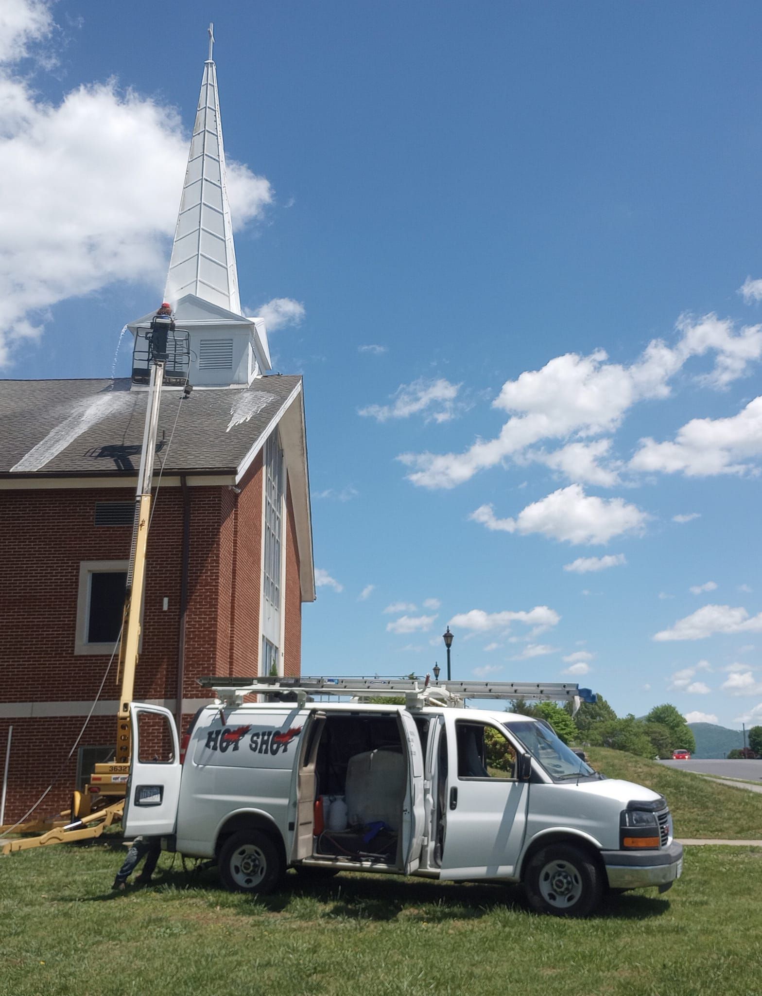 A white van is parked in front of a church