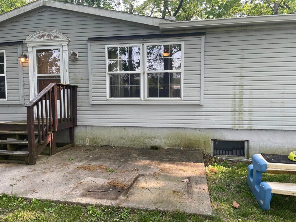 A mobile home with a deck and stairs is for sale.