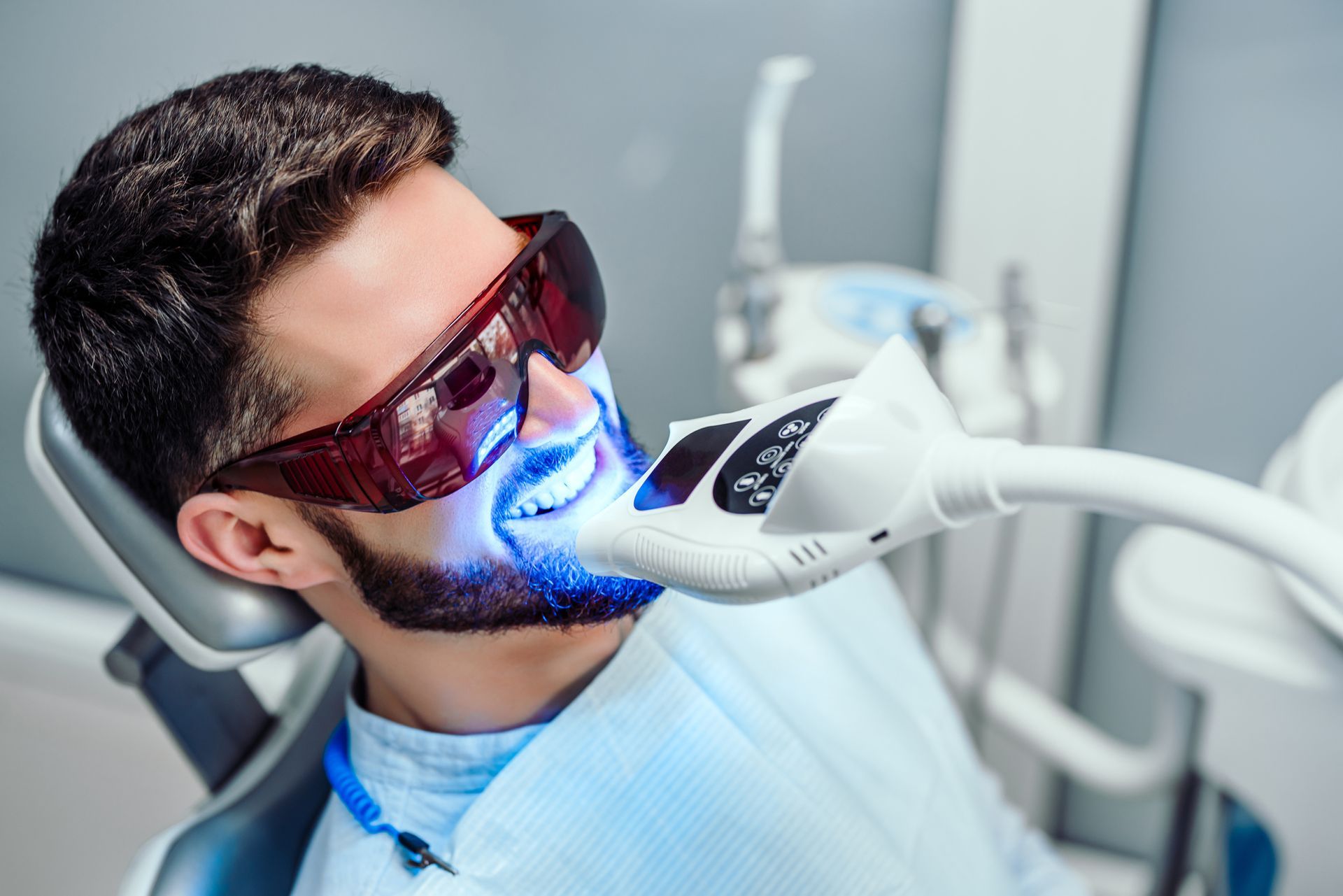 Man in a dental chair with blue light, showcasing teeth whitening services in Naples, NY by Dansvill