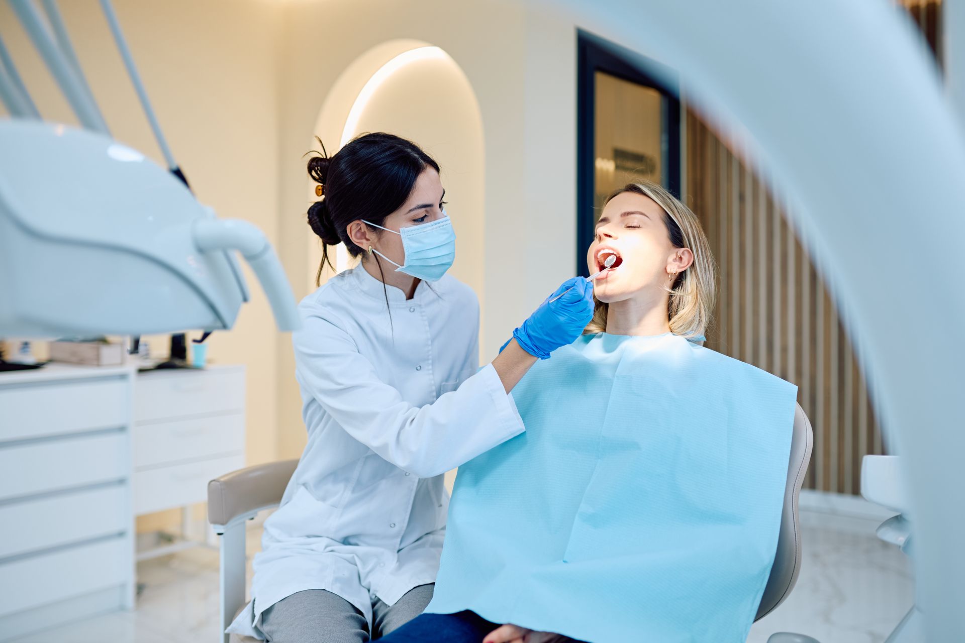 A dentist is checking the mouth of a patient.