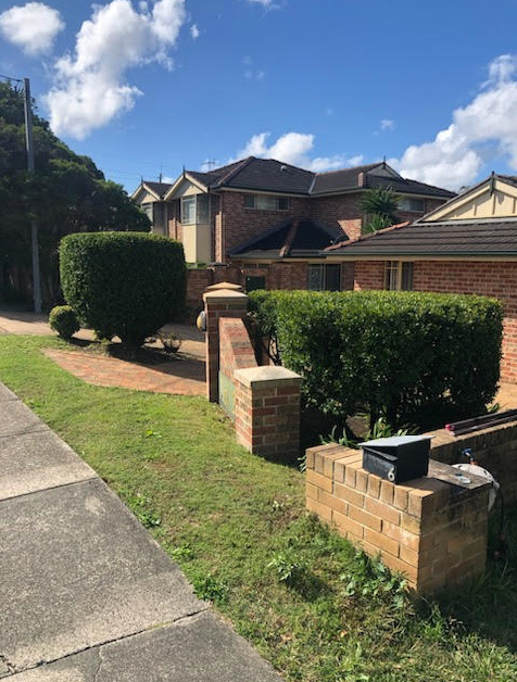 Charming Brick House with Black Fence in Pristine Garden Setting — Craig’s Lawn Mowing and Garden Maintenance