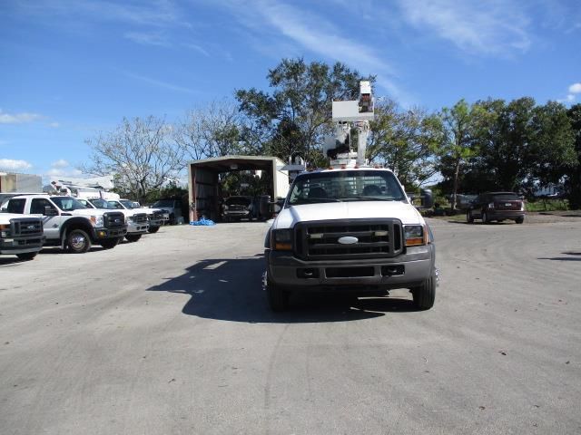 A white truck with a ladder on top is parked in a parking lot