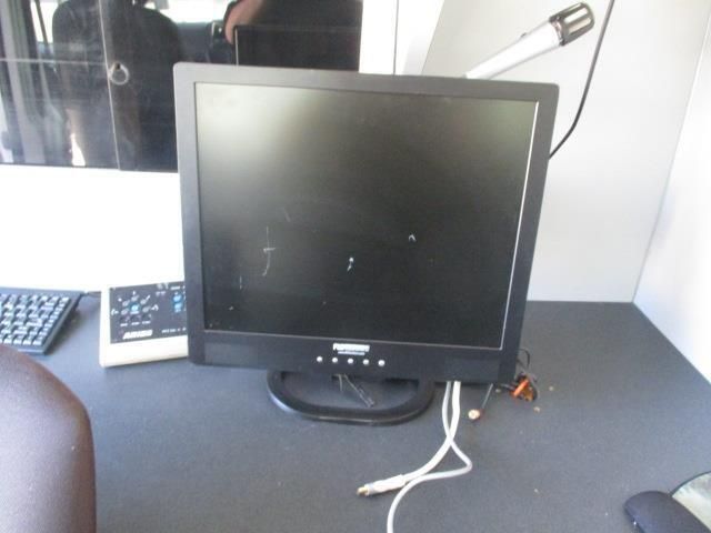 A computer monitor sits on a desk next to a remote control