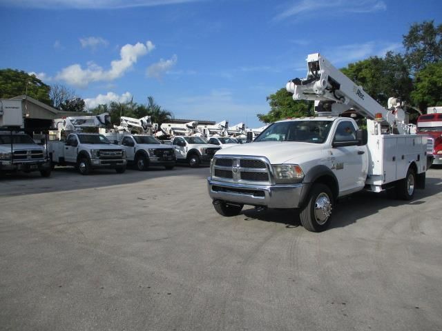 A row of utility trucks are parked in a parking lot