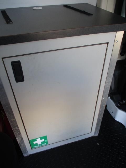 A white cabinet with a green sticker that says first aid on it