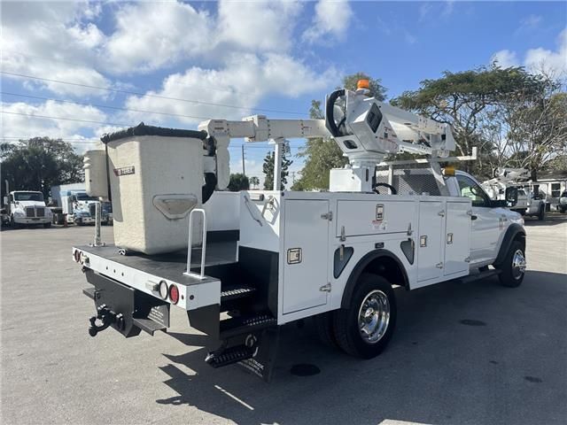 A white utility truck with a bucket on the back is parked in a parking lot.
