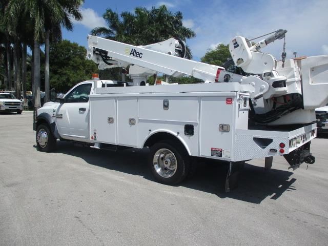 A white utility truck with a crane on the back is parked in a parking lot.