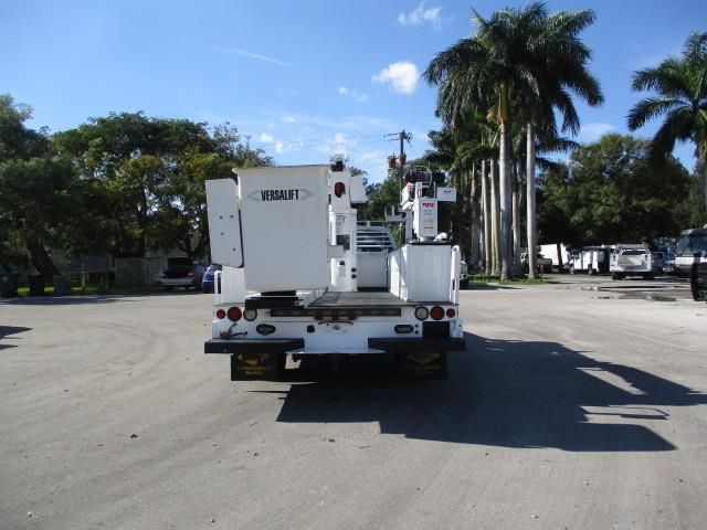 A white utility truck is parked in a parking lot with palm trees in the background