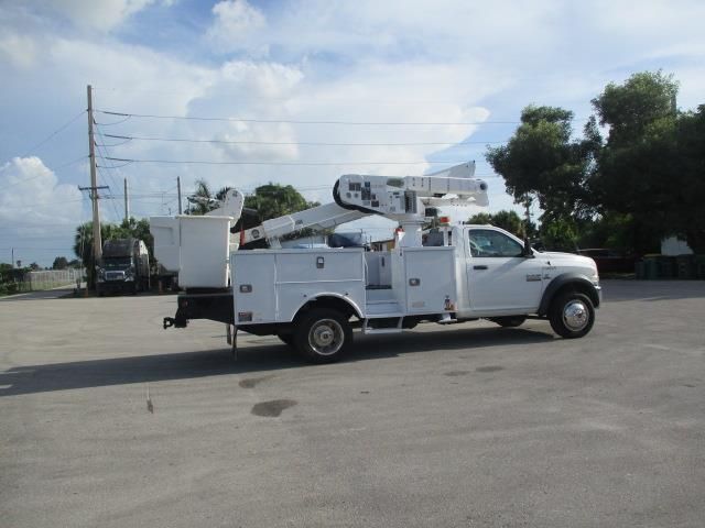 A white truck with a crane on the back is parked in a parking lot.