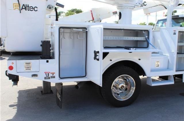 A white altec utility truck is parked in a parking lot