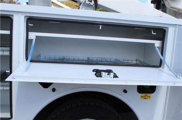 A white truck has a toolbox with the door open