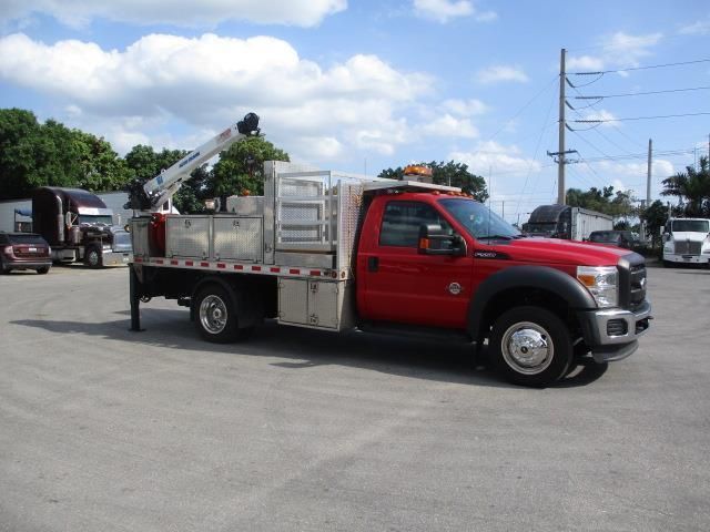 A red truck with a crane on the back is parked in a parking lot