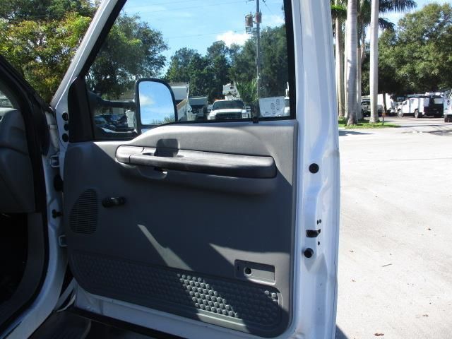 A white truck is parked in a parking lot with the door open