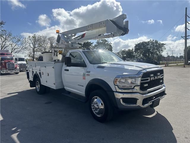 A white utility truck with a crane on top of it is parked in a parking lot.