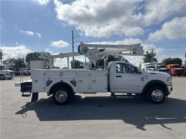 A white utility truck with a crane on the back is parked in a parking lot.