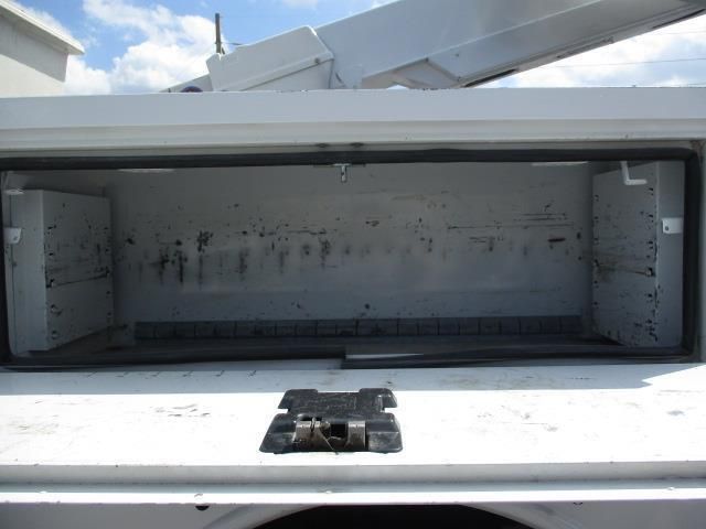 The back of a white truck with a toolbox open.