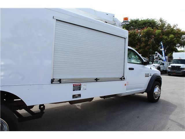 A white truck with a shutter on the side is parked in a parking lot.