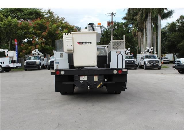 A utility truck is parked in a parking lot with other trucks