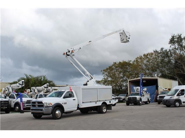 A white truck with a crane on the back is parked in a parking lot.