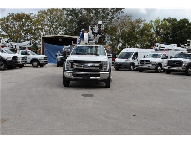 A row of utility trucks are parked in a parking lot