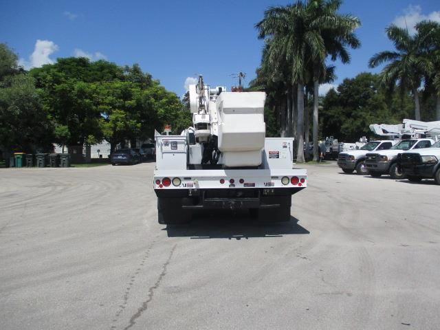 A white truck is parked in a parking lot with palm trees in the background