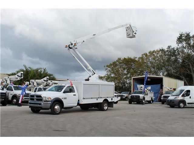 A white truck with a crane on the back is parked in a parking lot