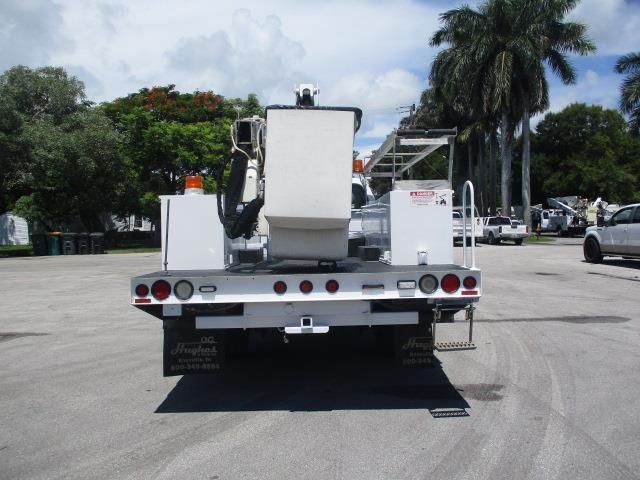 A white truck with a ladder on the back is parked in a parking lot