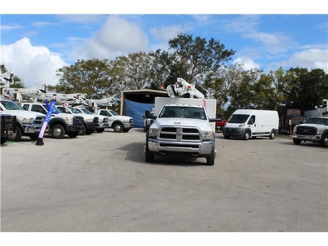 A row of white trucks are parked in a parking lot