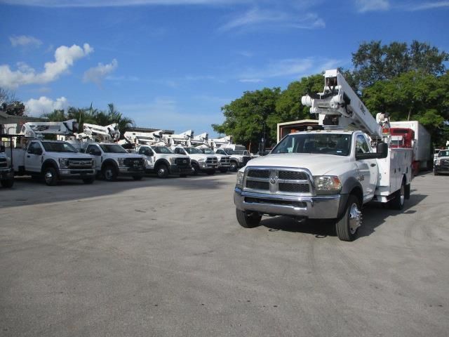 A row of utility trucks are parked in a parking lot