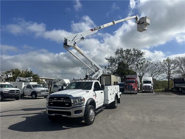 A white truck with a crane attached to it is parked in a parking lot.