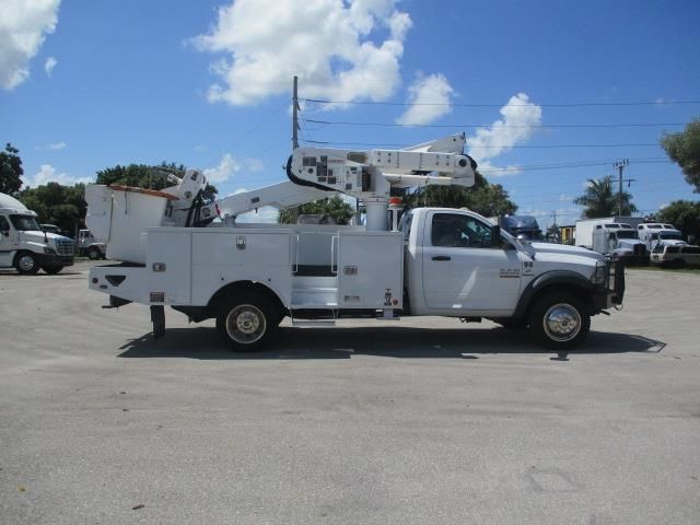 A white truck with a crane on the back is parked in a parking lot.