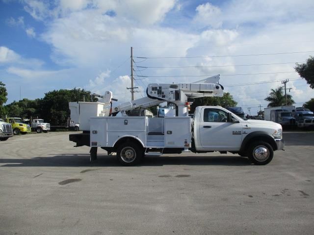 A white truck with a crane on the back is parked in a parking lot.