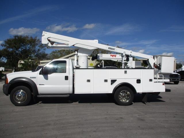 A white utility truck with a crane on the back is parked in a parking lot.