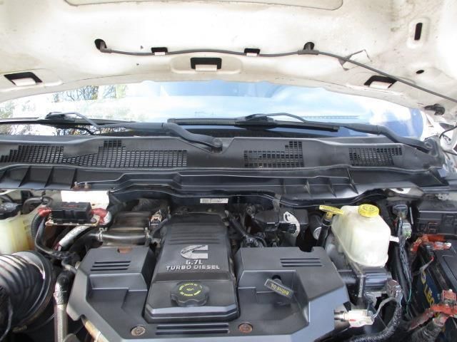 The engine of a white truck is shown with the hood open