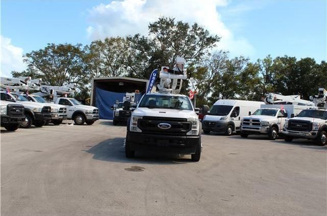 A row of white trucks are parked in a parking lot