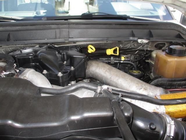 A close up of a car engine with a yellow dipstick
