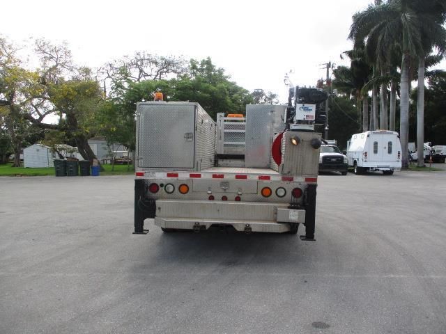 A silver truck is parked in a parking lot with trees in the background.