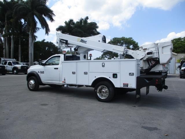 A white utility truck with a crane on the back is parked in a parking lot.
