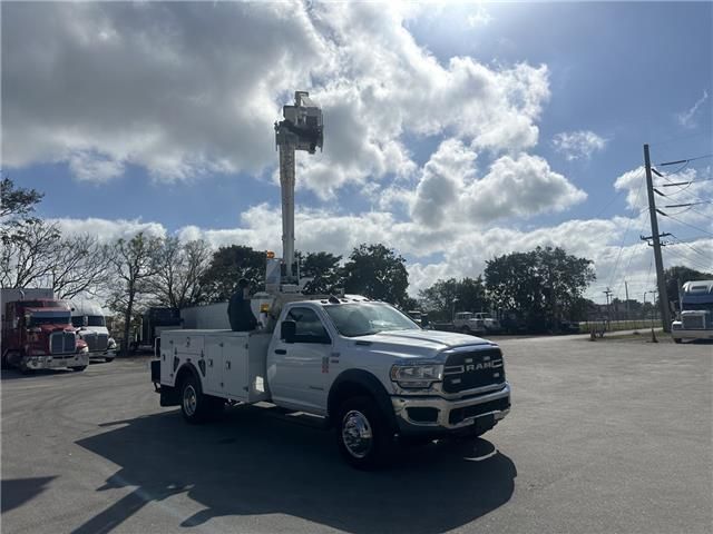 A white truck with a crane on the back is parked in a parking lot.