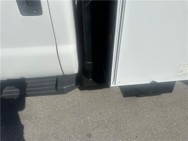A white truck is parked next to a white refrigerator.