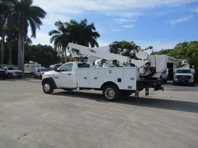 A white utility truck with a crane on the back is parked in a parking lot.