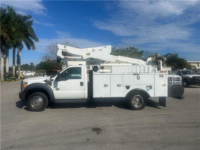 A white utility truck with a ladder on the back is parked in a parking lot.