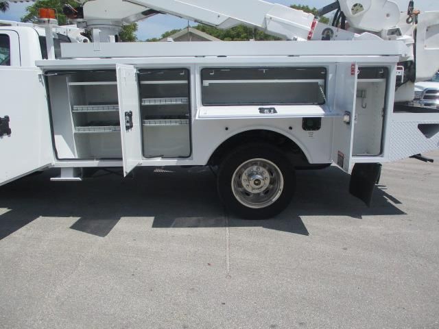 A white utility truck with the doors open is parked on the side of the road.